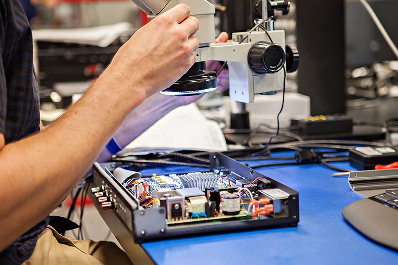 VR Employee using microscope to view internal components of a vibration controller