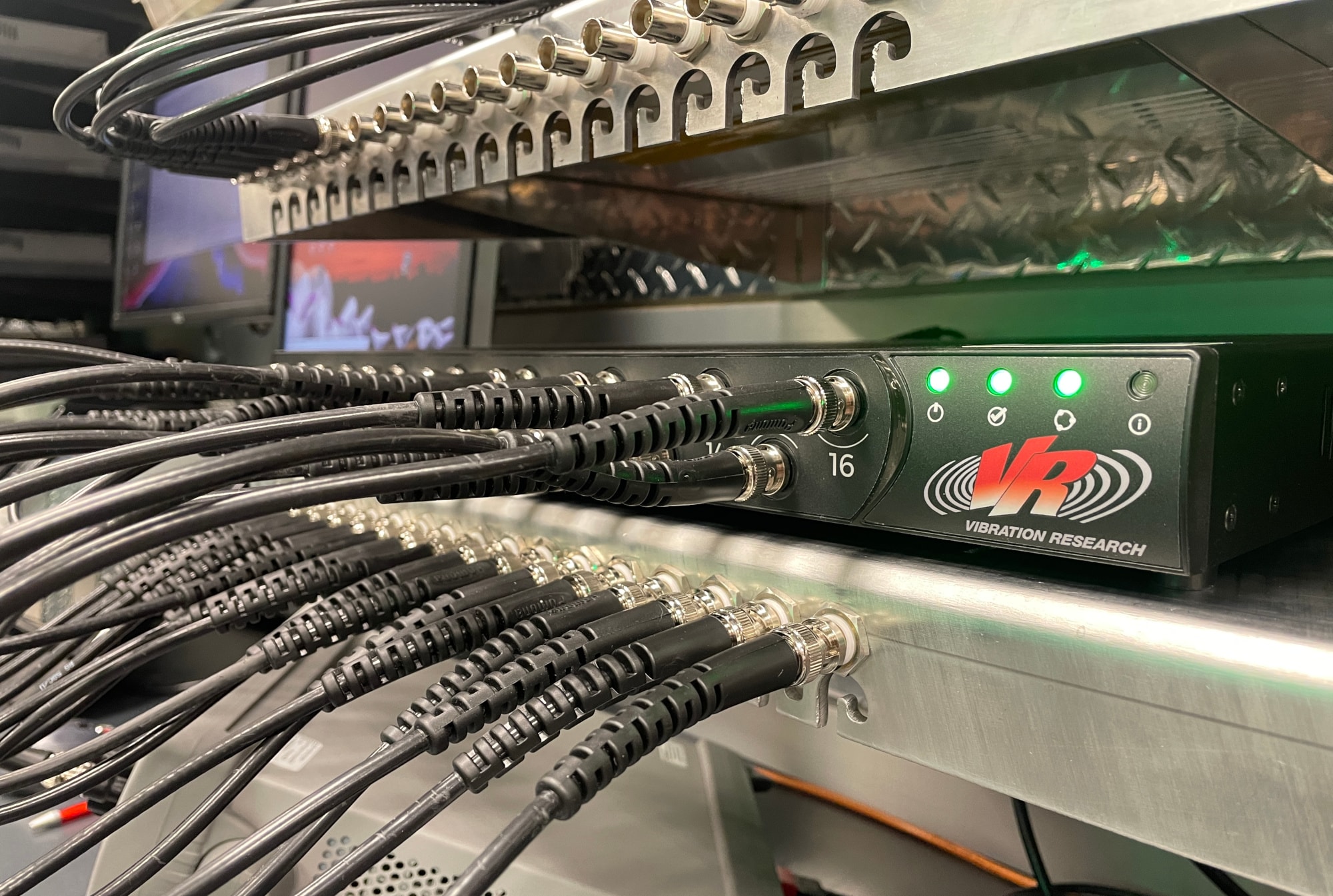 A VR10500 vibration controller on a rack and connected to input cables for calibration.