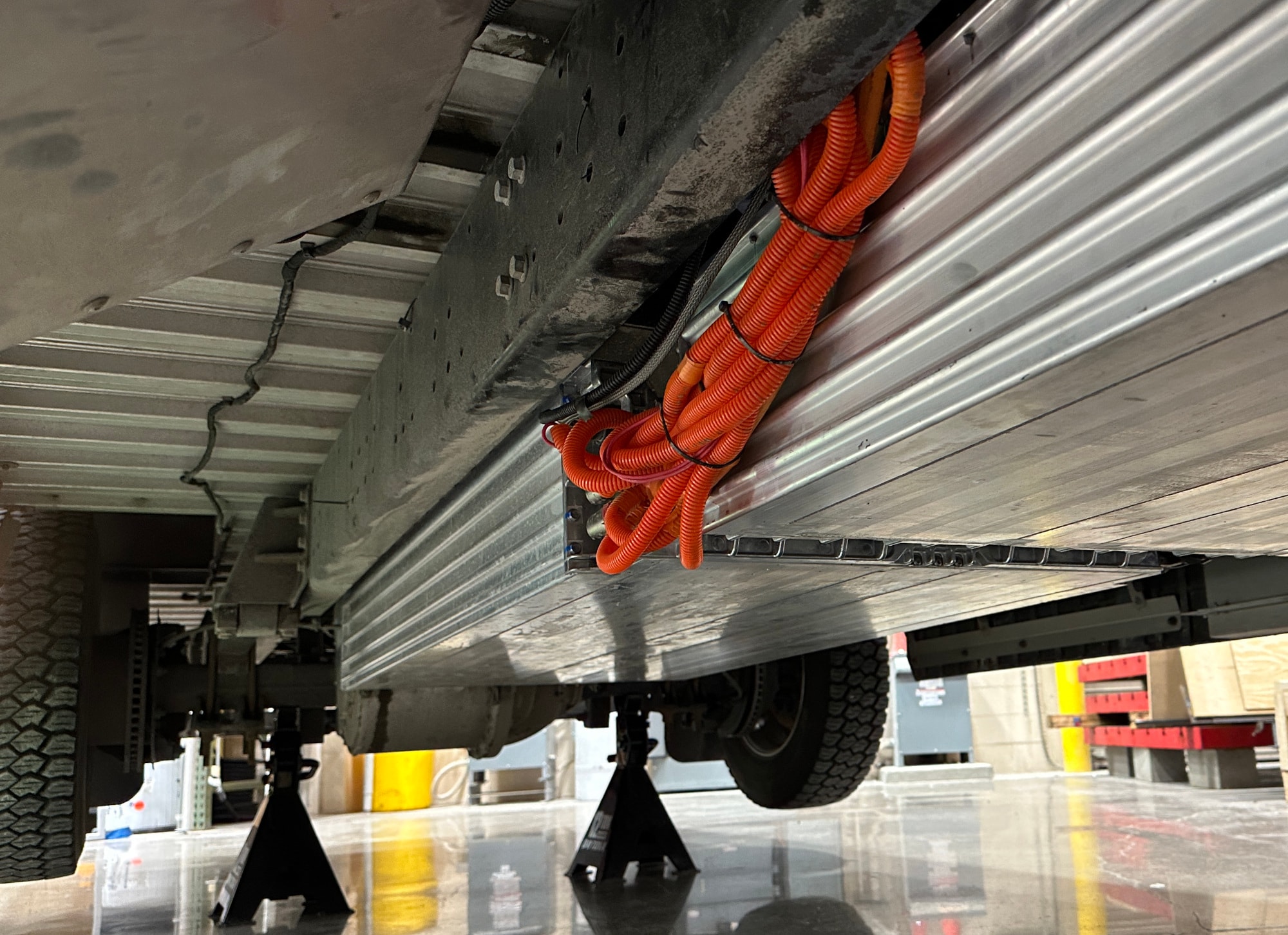 The underside of an electric vehicle on jacks displaying the battery packs.